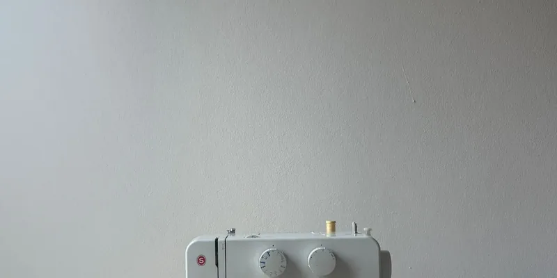 Naaimachine met stof op tafel tegen lichte muur